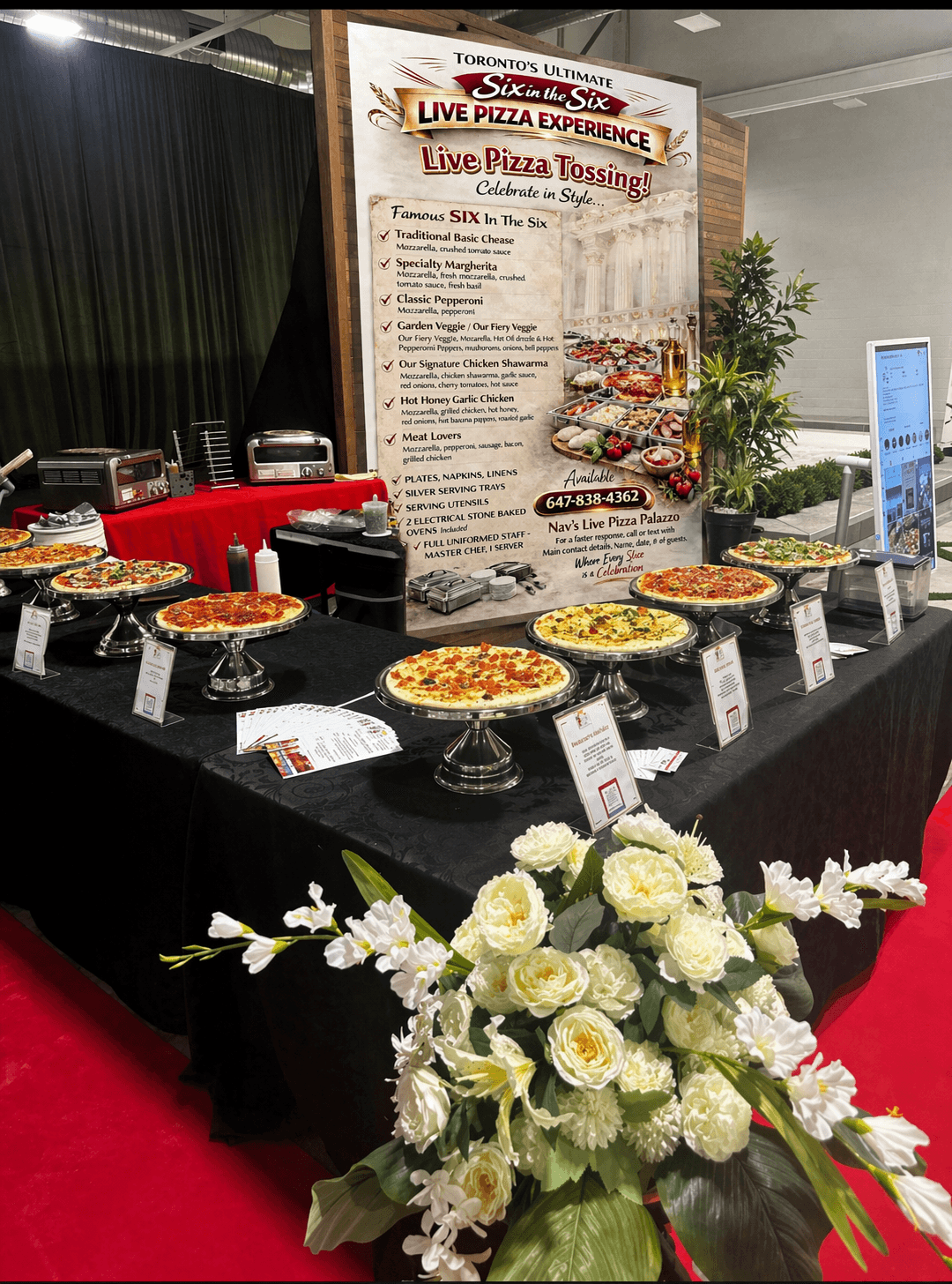 Full Six in the Six live pizza booth with menu banner, silver stands and white floral arrangement