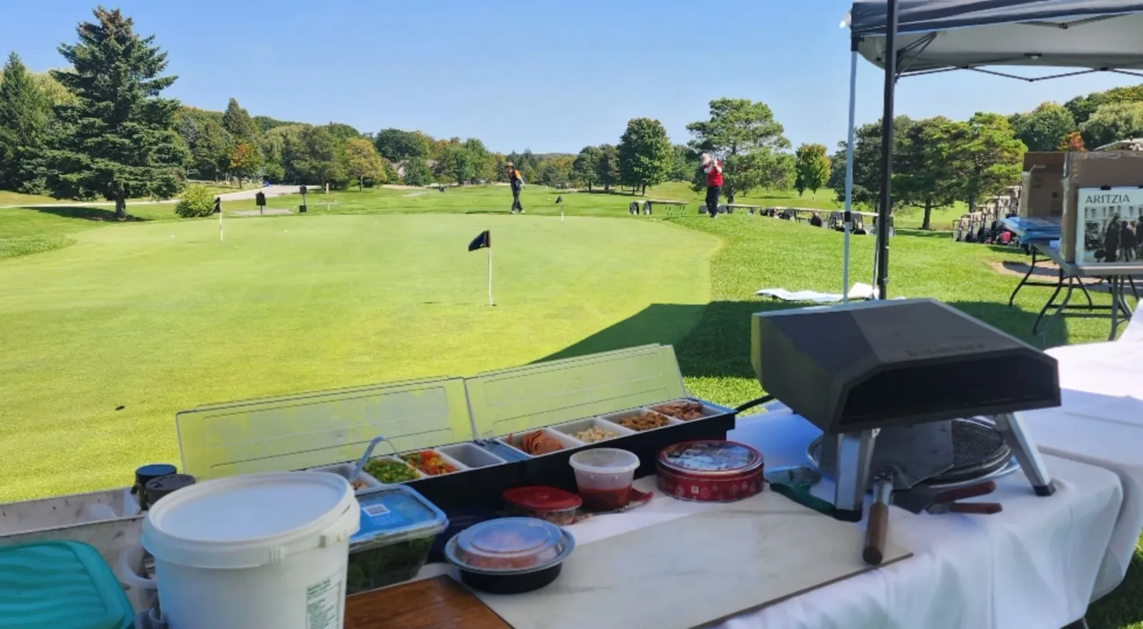 Live pizza station set up overlooking a manicured golf course green on a sunny day