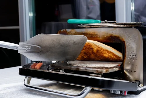 Portable stone oven baking pizza at a live station