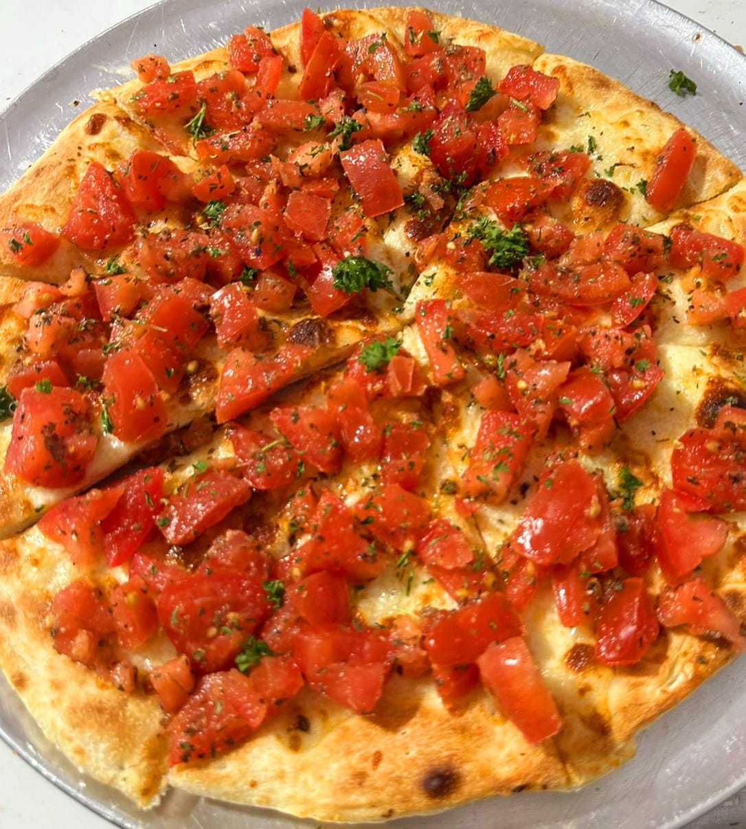 Close-up of a bruschetta gourmet pizza with diced tomato, herbs and balsamic on a white base