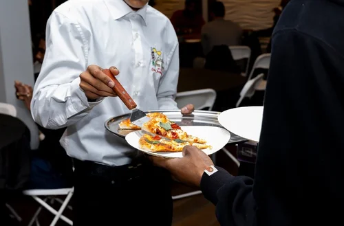 Server presenting a fresh pizza to guests
