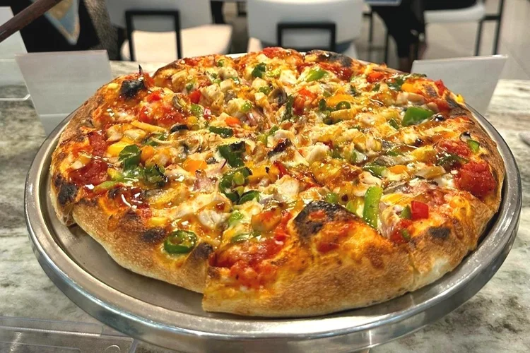 Stone-baked loaded vegetable pizza on a silver tray